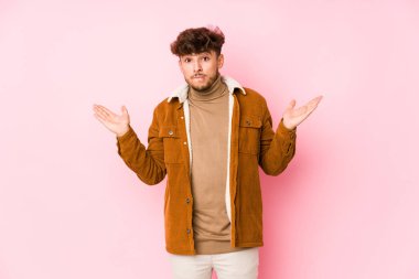 Pembe arka planda poz veren genç bir Arap.