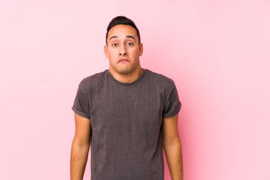 Yog Latin adam pembe arka planda poz veriyor omuzlarını silkeliyor ve gözleri açık..