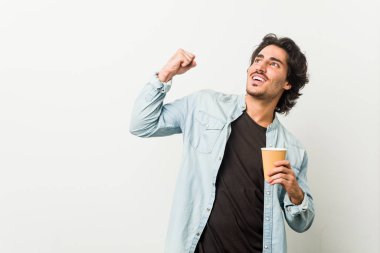 Genç havalı adam kahve içiyor zaferden sonra yumruk kaldırıyor, kazanan konsept..