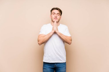 Kafkasyalı genç adam, yalnız poz veriyor. El ele tutuşup, ağzının kenarında dua ediyor. Kendine güveniyor..