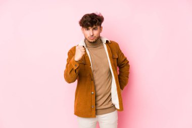 Pembe arka planda poz veren genç bir Arap.