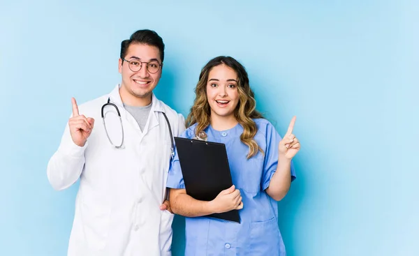 Mavi Arka Planda Poz Veren Genç Doktor Çift Iki Parmağı — Stok fotoğraf