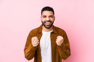 Pembe arka planda genç bir latin adam yalnız, kaygısız ve heyecanlı. Zafer konsepti.