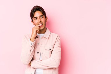 Pembe arka planda poz veren beyaz genç bir adam izole edilmiş bir şekilde rahat bir şekilde fotokopi odasına bakan bir şeyi düşünüyor..