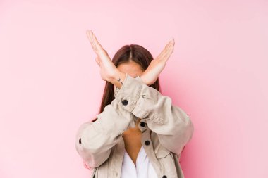 Pembe arka planda poz veren genç beyaz kadın iki kolu çapraz tutuyor, inkar kavramı.