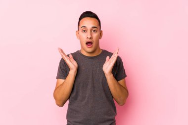 Pembe arka planda poz veren yog latin adam şaşırdı ve şok oldu..