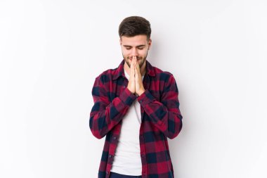 Beyaz arka planda poz veren beyaz tenli genç bir adam yalnız başına el ele tutuşup dua ediyor, kendinden emin hissediyor..