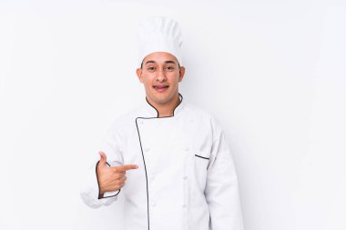 Young latin chef man isolated person pointing by hand to a shirt copy space, proud and confident clipart