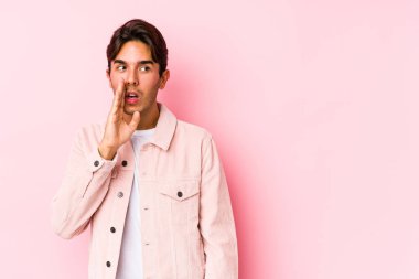 Pembe arka planda poz veren genç beyaz adam gizli bir sıcak fren haberi veriyor ve yana bakıyor.