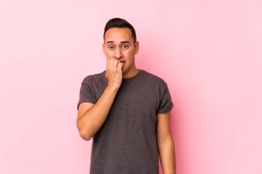 Pembe arka planda poz veren, tedirgin ve endişeli Latin bir adam..