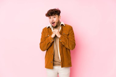 Pembe arka planda poz veren genç bir Arap.