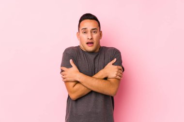 Pembe arka planda poz veren yog latin adam düşük ateş ya da hastalık yüzünden soğuktan donuyor..