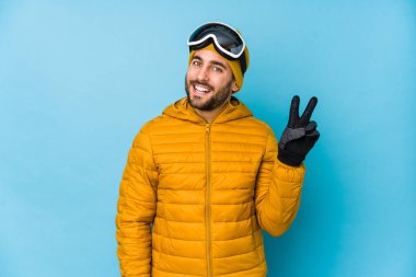 Genç kayakçı beyaz adam neşeli ve kaygısız izole edilmiş parmaklarıyla barış sembolü gösteriyor..