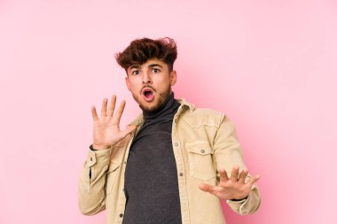 Arka planda poz veren genç bir Arap, yaklaşan bir tehlike nedeniyle şok geçiriyor.