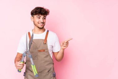 Genç Arap bahçıvan izole edilmiş gülümseyen ve işaret eden boş alanda bir şey gösteriyor..