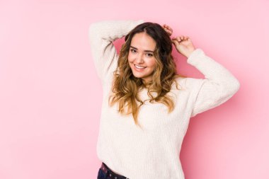 Pembe arka planda poz veren kıvrımlı genç kadın izole edilmiş kollar, rahat konum.