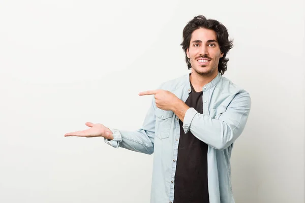 Jovem Homem Bonito Contra Fundo Branco Animado Segurando Espaço Cópia — Fotografia de Stock