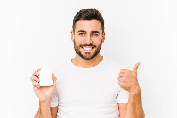 Joven Hombre Caucásico Sosteniendo Una Botella Vitaminas Aislado Sonriendo Levantando —  Fotos de Stock