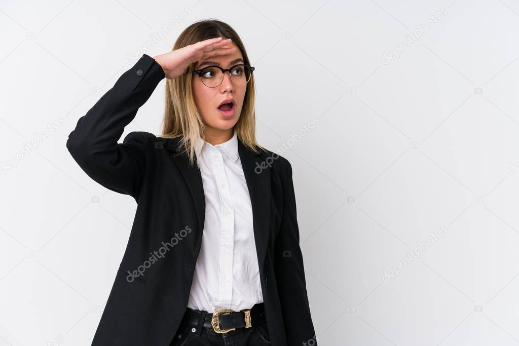 Young business caucasian woman looking far away keeping hand on forehead.