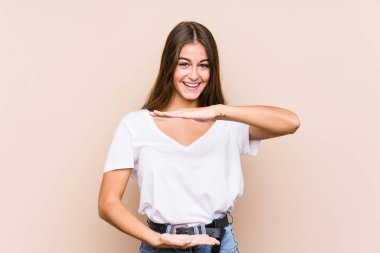 Kafkasyalı genç bir kadın iki eliyle bir şey tutuyormuş gibi poz veriyor, ürün sunumu..