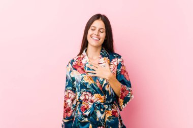 Kimono pijama giyen beyaz bir kadın elini göğsüne koyduğunda kahkahalar atıyor..