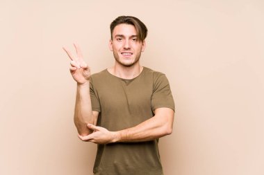 Kafkasyalı genç adam yalnız poz veriyor neşeli ve kaygısız parmakları olan bir barış sembolü gösteriyor..