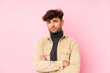 Arka planda poz veren genç bir Arap adam kameraya alaycı bir ifadeyle bakıyor..