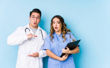 Mavi arka planda poz veren genç doktor çiftin elleri arasında bir fotokopi alanı olması şaşırtıcı ve şok edici..