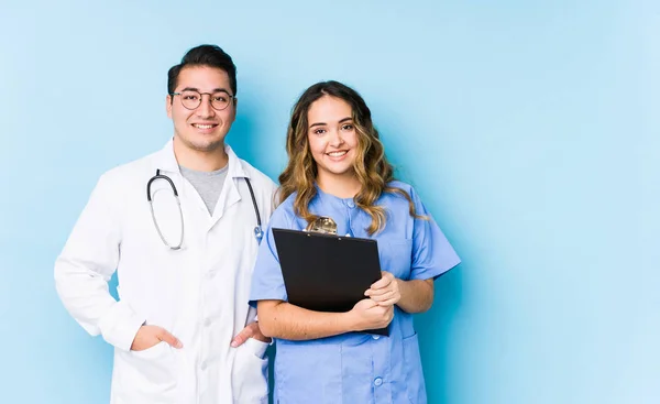 Young Doctor Couple Posing Blue Background Isolated Happy Smiling Cheerful — 스톡 사진