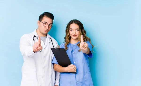Mavi Arka Planda Poz Veren Genç Doktor Çift Bir Numarayı — Stok fotoğraf