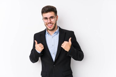 Beyaz arka planda poz veren beyaz tenli genç bir iş adamı genç beyaz tenli bir iş adamını yalnız bırakıp iki parmağını da kaldırıyor, gülümsüyor ve kendinden emin.