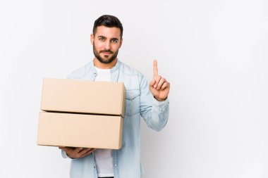 Genç, beyaz bir adam yeni evine taşınıyor. Bir numarayı parmağıyla gösteriyor..