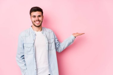 Beyaz arka planda poz veren beyaz tenli genç bir iş adamı bir avuç içinde fotokopi alanı ve belinde bir el daha gösteriyor. 