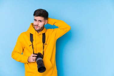 Kafkasyalı genç fotoğrafçı kafasının arkasına dokunuyor, düşünüyor ve bir seçim yapıyor..