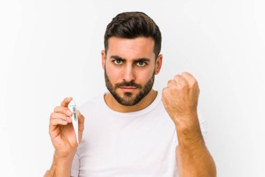 Termometre tutan genç beyaz bir adam kameraya yumruk sallayan genç beyaz bir adam, agresif bir yüz ifadesi..