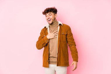 Pembe arka planda poz veren genç bir Arap.