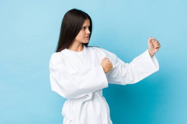 Mavi arka planda karate yapan beyaz bir kadın.