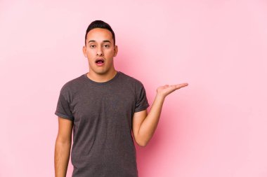 Yooung Latin adam pembe arka planda poz veriyor. Elinde fotokopi alanı tutuyor..