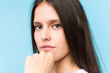 Kafkasyalı genç bir kızın yüzü, mavi bir arka planda izole bir şekilde yakından çekilmiş.