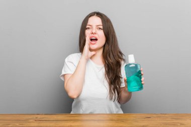 Genç ve kıvrımlı bir kadın elinde gargara tutarak heyecanla bağırıyor..