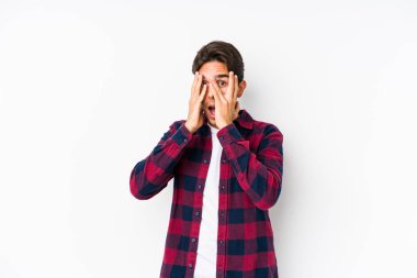 Pembe arka planda poz veren beyaz bir genç parmaklarıyla korkmuş ve gergin bir şekilde göz kırpıyor..