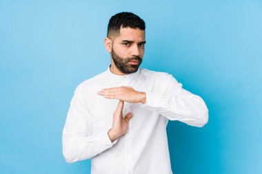 Mavi arka planda genç bir latin adam izole edilmiş bir şekilde mola veriyor..