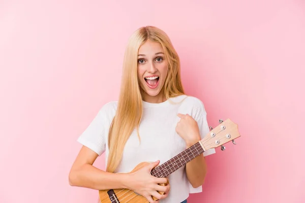 Giovane Ragazza Bionda Giocare Ukelele Sorpreso Indicando Stesso Sorridendo Ampiamente — Foto Stock