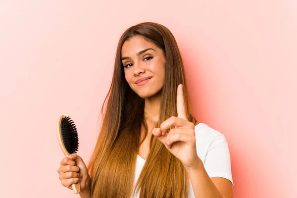 Young Caucasian Woman Holding Hairbrush Showing Number One Finger — Stockfoto