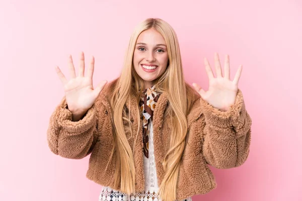 年轻的金发女人穿着一件粉色背景的外套 手上拿着十号牌 — 图库照片