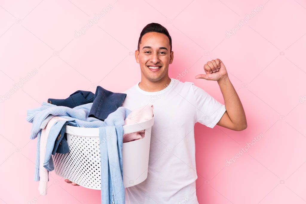 Young latin man picking up dirty clothes isolated feels proud and self confident, example to follow.