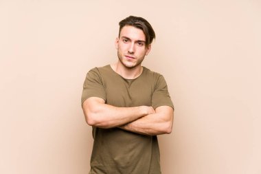 Kafkasyalı genç adam, yalnız poz veriyor hoşnutsuzca surat asıyor, kollarını kavuşturuyor..
