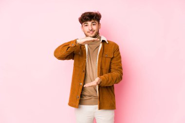 Pembe arka planda poz veren genç bir Arap.