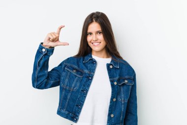 Genç, sevimli bir kadın, parmakları küçük bir şey tutuyor, gülümsüyor ve kendinden emin..