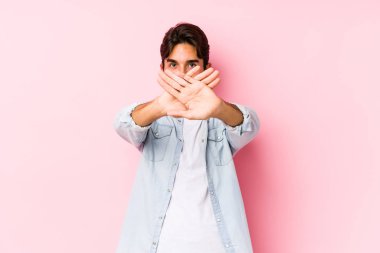 Pembe arka planda poz veren genç beyaz bir adam inkar jesti yapıyor.